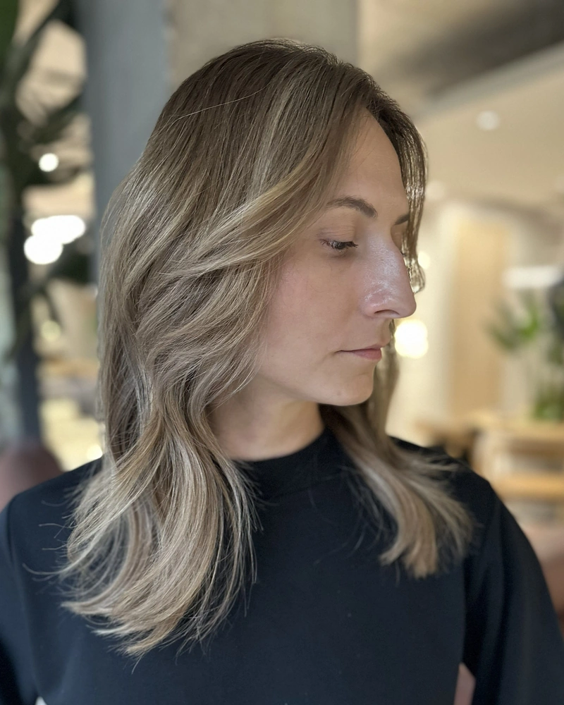 Balayage w jasnym blondzie, profil fryzury z miękką falą